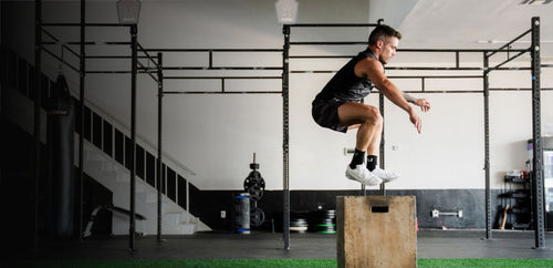 Athlete performing a box jump in a gym